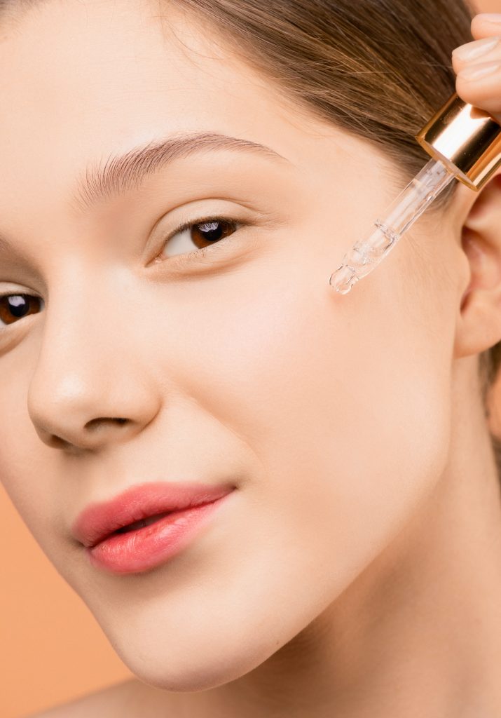 woman using facial serum with a dropper